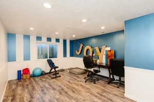 Workout room featuring LVP finished floors, a textured ceiling, recessed lighting, and baseboards