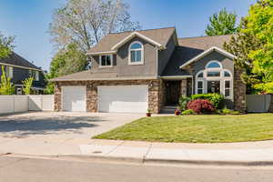 View of front of house featuring stucco siding, roof with shingles, driveway, a garage, and stone siding