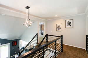 Corridor with an upstairs landing, carpet floors, a chandelier, crown molding, and baseboards