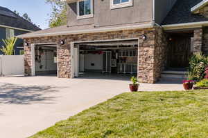 Property entrance with stone siding, concrete driveway, stucco siding, and a garage