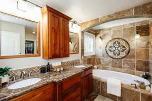 Full bath with tiled bath, double vanity, tile walls, a walk in closet, and backsplash