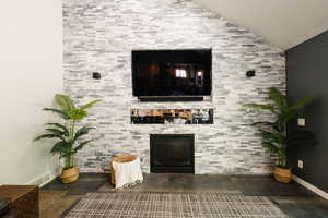 Living area featuring a fireplace, lofted ceiling, and baseboards