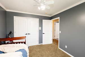 Bedroom featuring carpet flooring, a closet, crown molding, baseboards, and a ceiling fan