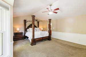 Carpeted bedroom featuring vaulted ceiling, ceiling fan, and baseboards