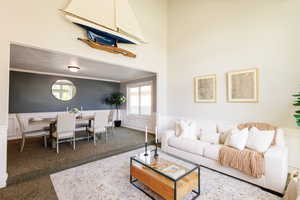 Carpeted living room featuring a wainscoted wall, plenty of natural light, crown molding, and a decorative wall