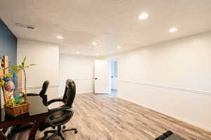 Office space featuring a textured ceiling, recessed lighting, light LVP-style flooring, and baseboards