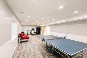 Recreation room with wood finished floors, recessed lighting, arched walkways, and baseboards