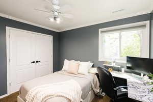 Bedroom with carpet flooring, a closet, crown molding, and a ceiling fan