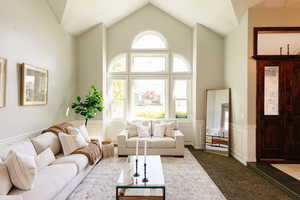 Living area with wainscoting, high vaulted ceiling, and a decorative wall