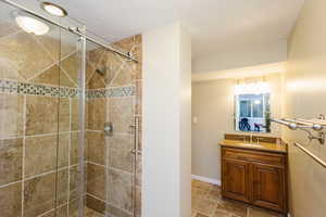 Full bathroom with a stall shower, vanity, baseboards, and a textured ceiling