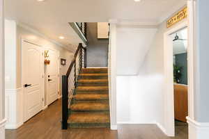Stairway with crown molding, recessed lighting, wood finished floors, and baseboards