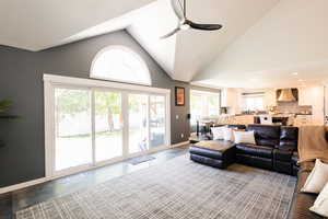 Living room with ceiling fan, baseboards, high vaulted ceiling, recessed lighting, and dark tile patterned flooring