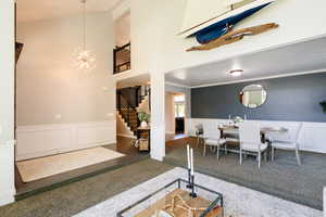 Living area with stairway, carpet, a chandelier, a wainscoted wall, and a decorative wall