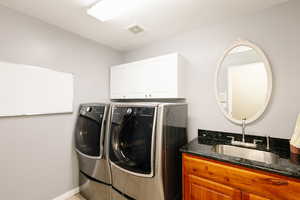 Washroom with washing machine and dryer, cabinet space, and baseboards