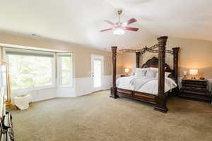 Carpeted bedroom featuring lofted ceiling and a ceiling fan