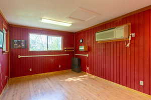 Spare room featuring wood finished floors, an AC wall unit, attic access, and wood walls