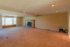 Unfurnished living room with light carpet, baseboards, a tiled fireplace, and recessed lighting