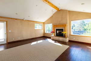 Unfurnished living room featuring dark wood-style flooring, a fireplace, and baseboards