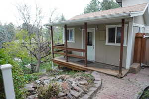 View of exterior entry featuring roof with shingles and fence