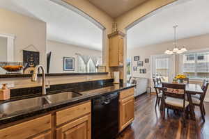 Kitchen with black appliances, dark wood flooring, dark stone counters, and recessed lighting