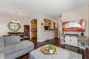 Living, dining and kitchen area featuring a chandelier dark wood-style flooring