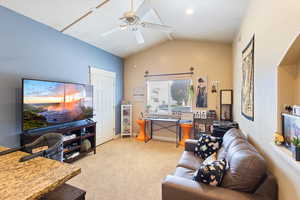Living area featuring light colored carpet, lofted ceiling, a desk, and ceiling fan