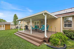 Wooden terrace with a lawn, a storage unit, an outdoor structure, area for grilling, and an outdoor living space