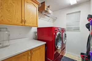 Laundry room featuring cabinet space, independent washer and dryer, baseboards, and light tile patterned floors