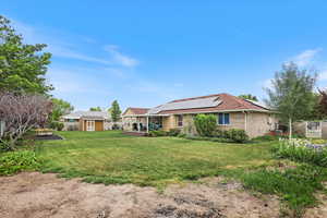 Back of house featuring roof mounted solar panels, an outdoor structure, a storage unit, and brick siding