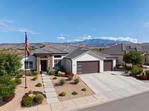 View of front facade with a garage, stucco siding, a mountain view, and driveway