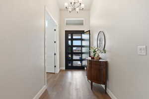 Entrance foyer with baseboards, a chandelier, and wood finished floors