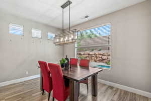 Dining area with a chandelier, healthy amount of natural light, light wood-style floors, and baseboards