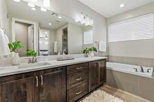 Bathroom featuring wood finished floors, double vanity, a garden tub, and ensuite bathroom