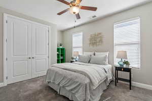 Carpeted bedroom with a closet, baseboards, and ceiling fan