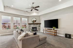 Living room with carpet, baseboards, ceiling fan, a fireplace, and recessed lighting