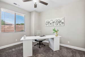 Home office featuring dark carpet, baseboards, and a ceiling fan
