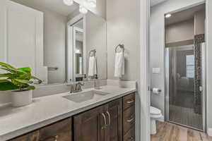 Bathroom with a shower stall, toilet, vanity, and wood finished floors
