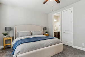 Carpeted bedroom with baseboards, ensuite bath, and a ceiling fan