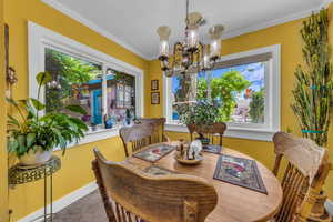 Dining space featuring a chandelier, carpet floors, crown molding, and baseboards