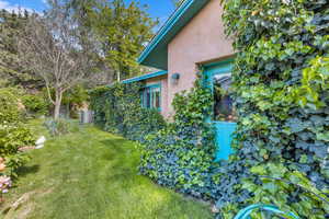 View of side of home with stucco siding and a yard