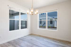 Spare room featuring a chandelier, baseboards, and wood finished floors