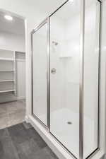 Full bathroom with a stall shower, a walk in closet, and recessed lighting