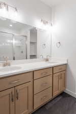 Full bath featuring double vanity, a stall shower, and baseboards