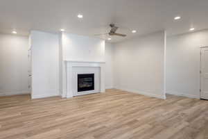 Unfurnished living room with ceiling fan, recessed lighting, light wood-style floors, a fireplace, and baseboards