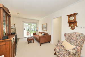 Living room featuring light colored carpet, crown molding, and recessed lighting