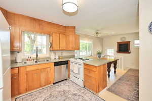 Kitchen featuring dishwasher, electric range, a sink, a peninsula, and fridge
