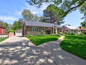 Ranch-style home featuring a detached garage, a chimney, and a front yard