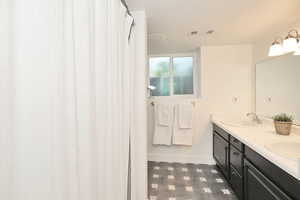 Bathroom featuring tile patterned floors, double vanity, and baseboards