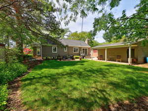 Rear view of property featuring entry steps, a patio area, a chimney, and a yard