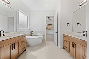 Full bath with a freestanding bath, two vanities, ceiling fan, and tile patterned floors
